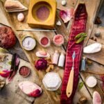 A creative flat lay with natural pigments, tools, and artistic elements on a wooden surface.